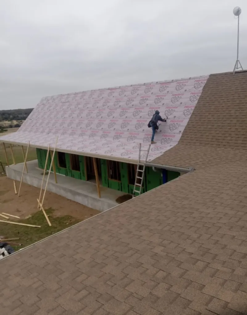 Worker preparing underlayment for a metal roof installation in Dunbar